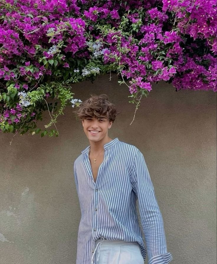 Chico de pie bajo una buganvilla