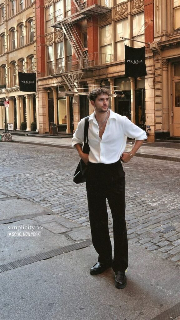 Chico de pie en una calle de ciudad con camisa blanca