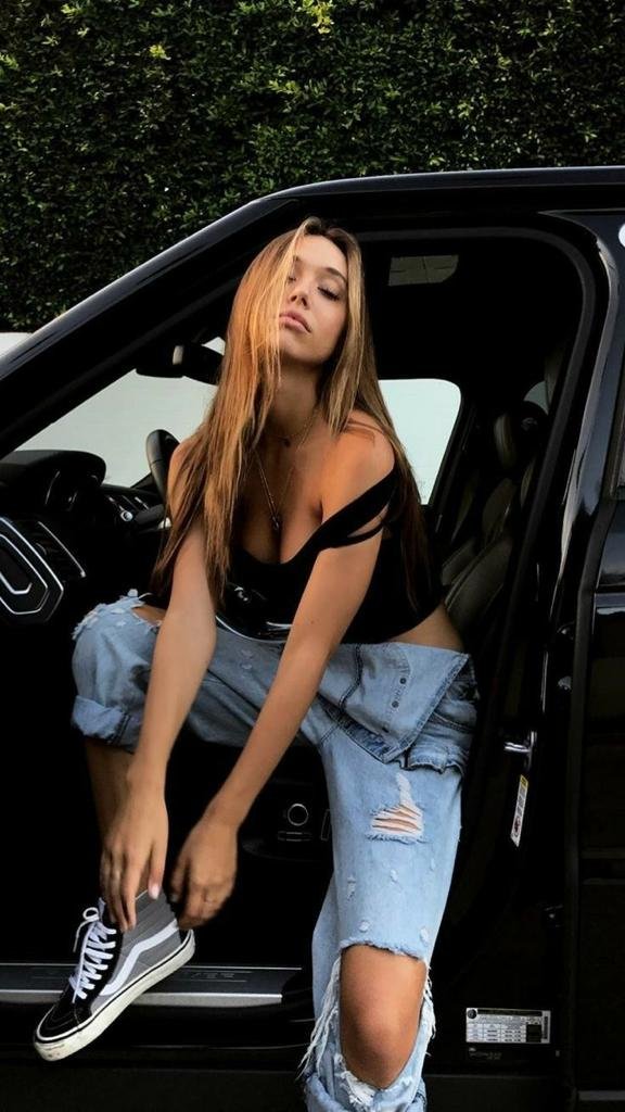 Chica sentada de lado con la puerta del coche abierta