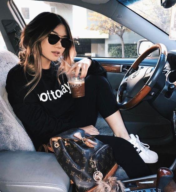 Chica al volante con gafas de sol y bebida