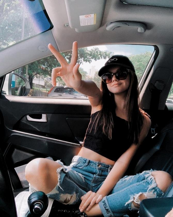 Chica sentada en el asiento del copiloto con gorra y gafas