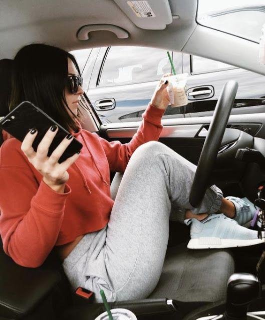 Chica sentada en el coche con una bebida