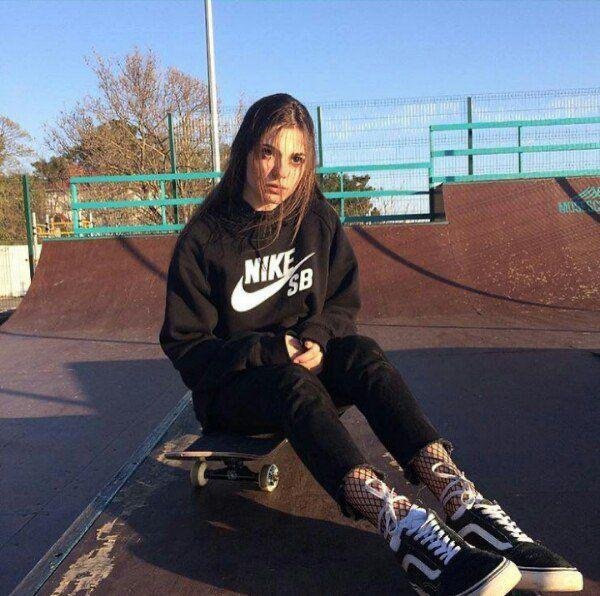 Chica sentada en un skatepark con un monopatín