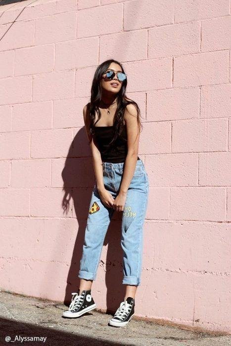 Chica apoyada en una pared rosa con gafas de sol