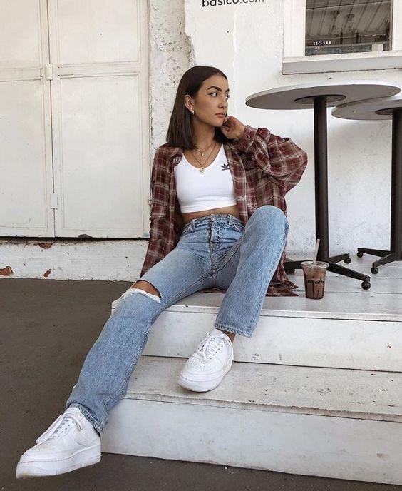 Camisa de cuadros con top blanco sentada en unas escaleras