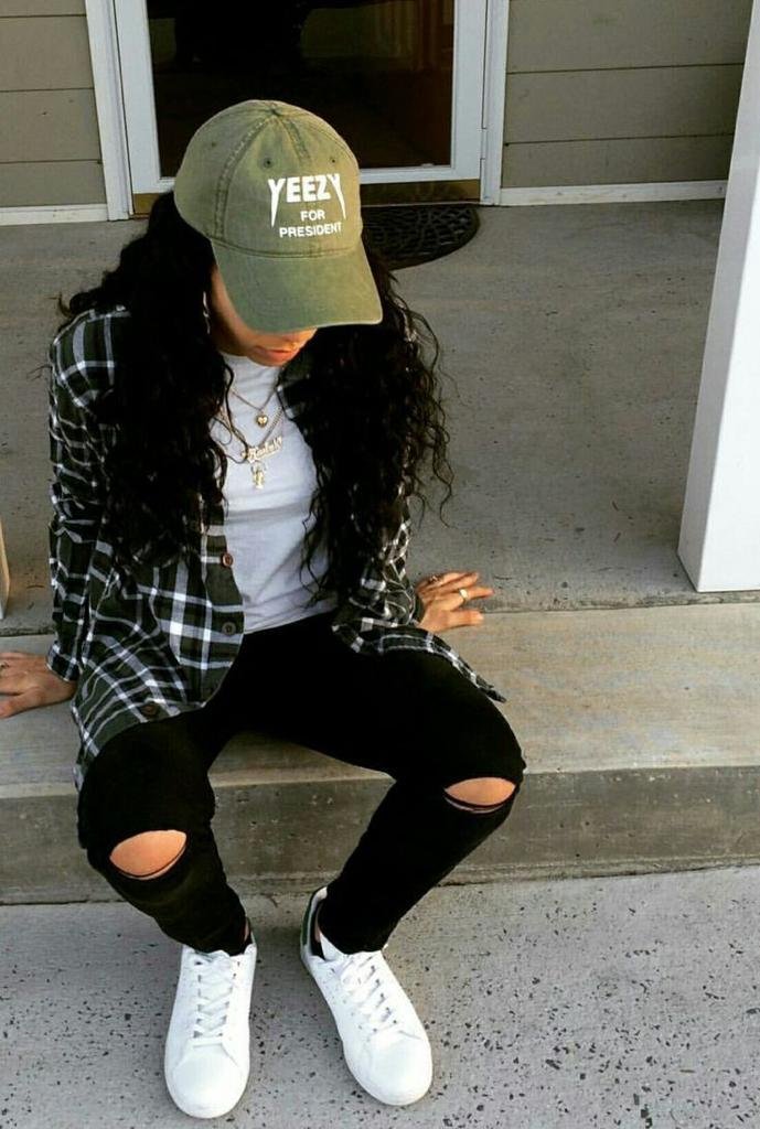 Camisa de cuadros abierta con jeans negros rotos y gorra