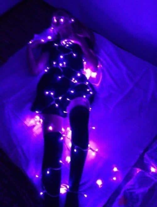 Chica con luces de colores sobre fondo morado