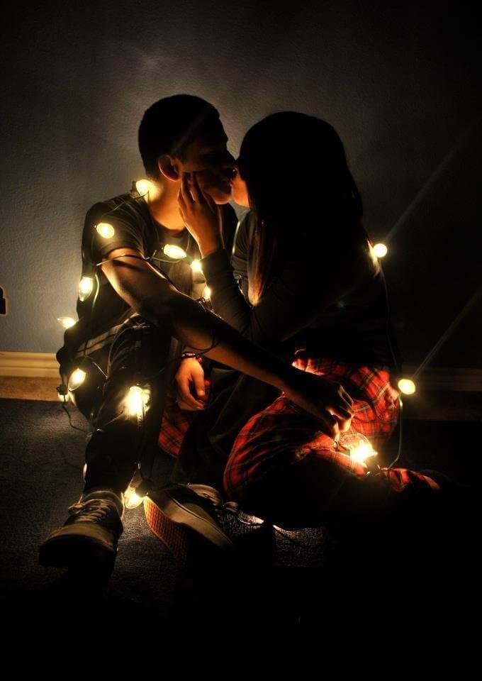 Pareja iluminada solo por una guirnalda de luces