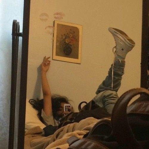 Chica tumbada en la cama con los pies apoyados en la pared