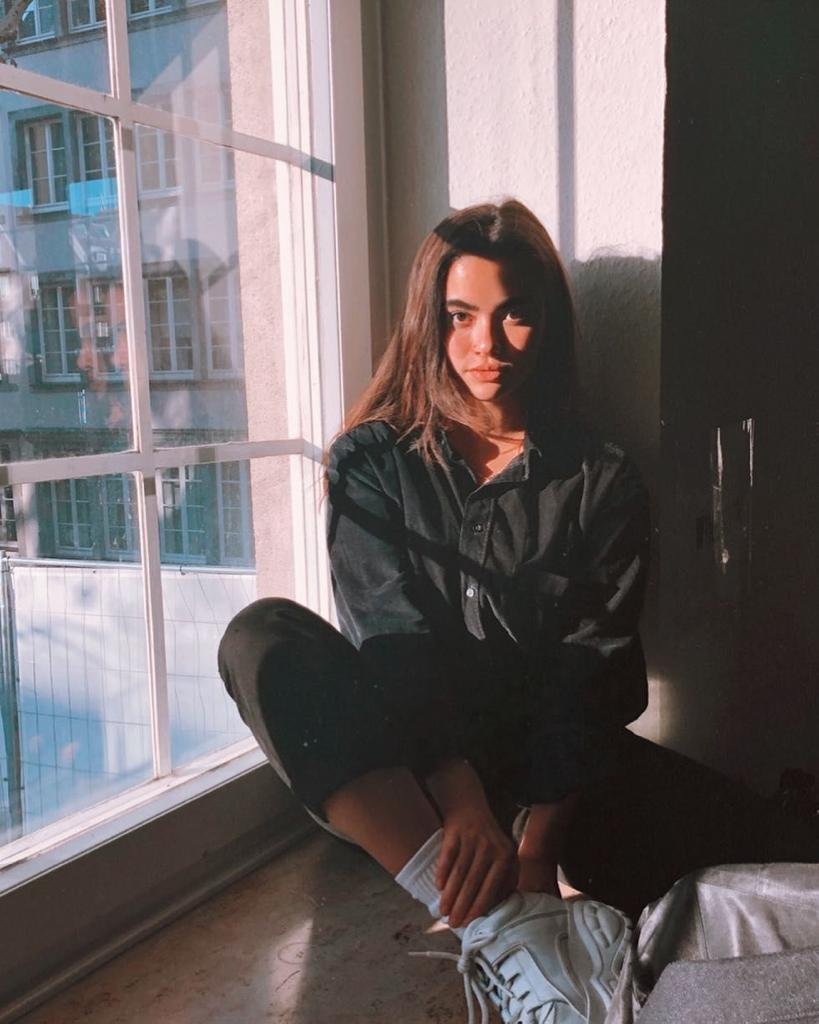 Chica sentada junto a la ventana con luz natural