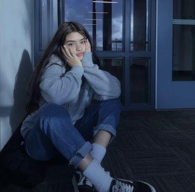 Chica sentada en el suelo junto a una puerta de cristal