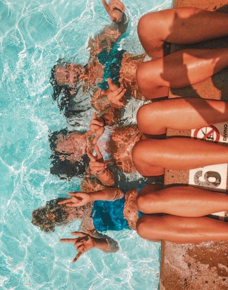 Piernas de varias personas al borde de la piscina desde arriba