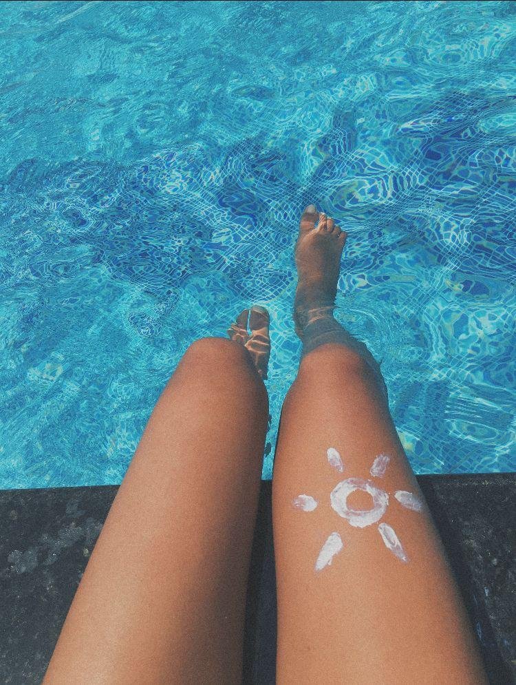 Piernas dentro del agua con un sol dibujado con crema