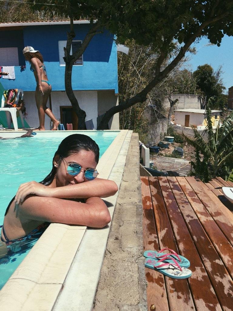 Chica apoyada en el borde de madera con gafas de sol