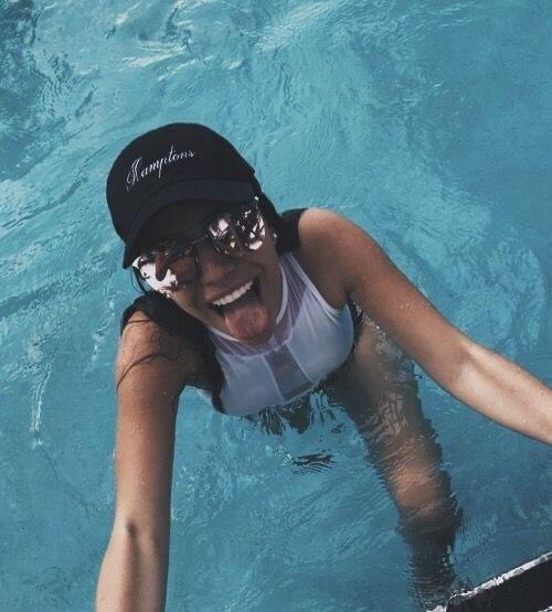 Chica saliendo del agua con gorra y bañador blanco