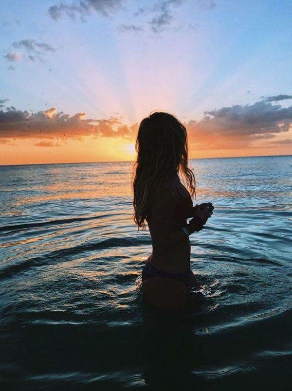 Chica de espaldas dentro del agua al amanecer