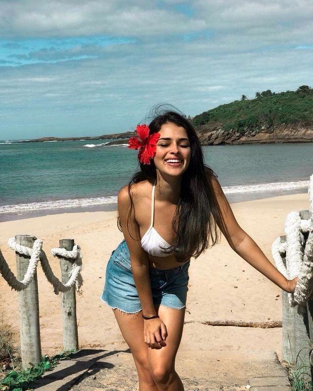 Chica caminando por la orilla con una flor en el pelo