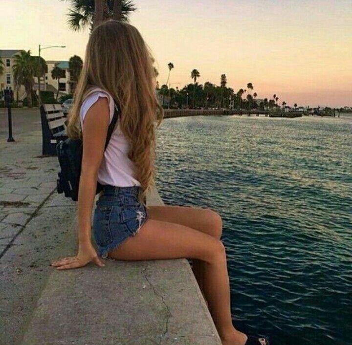 Chica sentada de espaldas en un muelle al atardecer