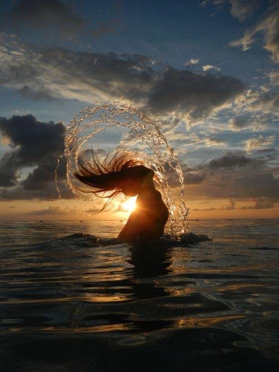 Chica sacudiendo el pelo dentro del agua a contraluz