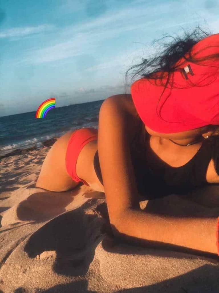 Chica tumbada en la arena con gorra roja