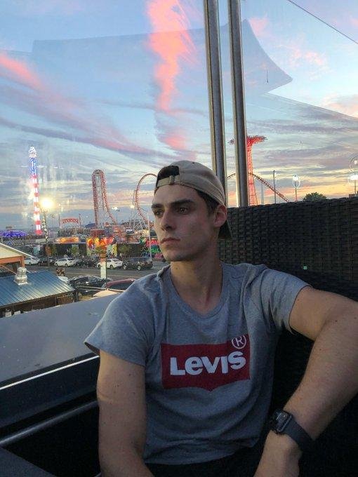 Chico sentado en una terraza al atardecer con camiseta gris