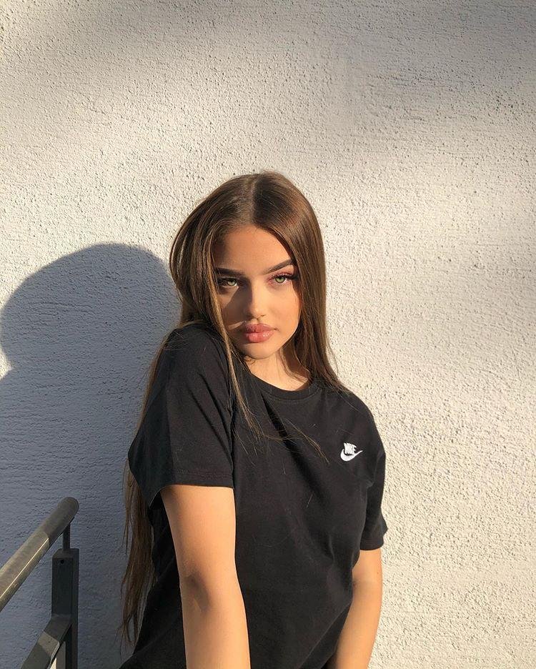 Chica de pie contra una pared lisa con camiseta negra