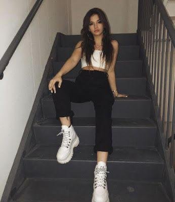 Chica sentada en unas escaleras con botas blancas