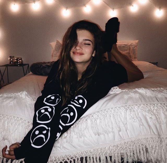 Chica tumbada en la cama con luces de fondo