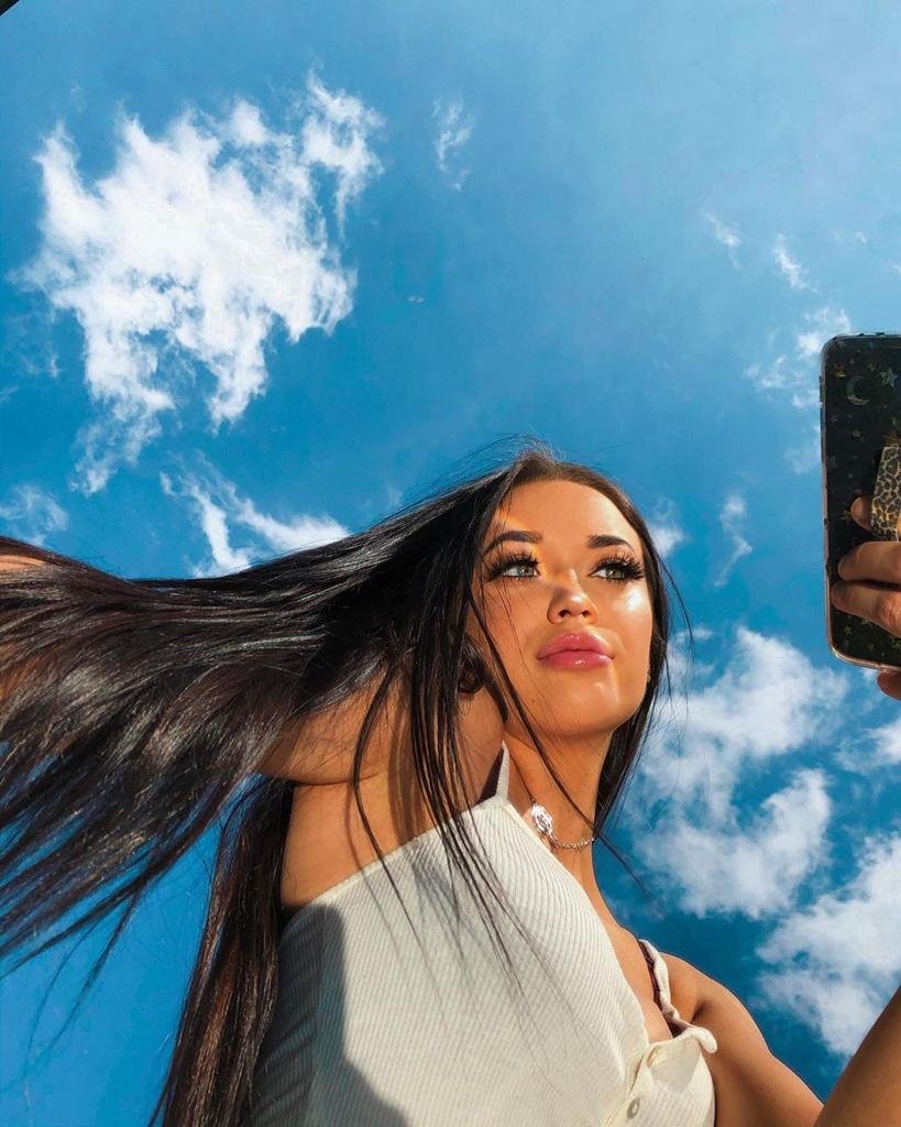 Foto desde abajo con el pelo al viento y el cielo de fondo