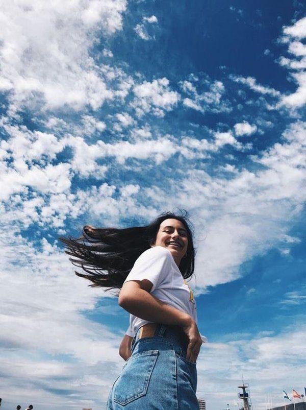 Chica con el cielo azul de fondo y el pelo en movimiento