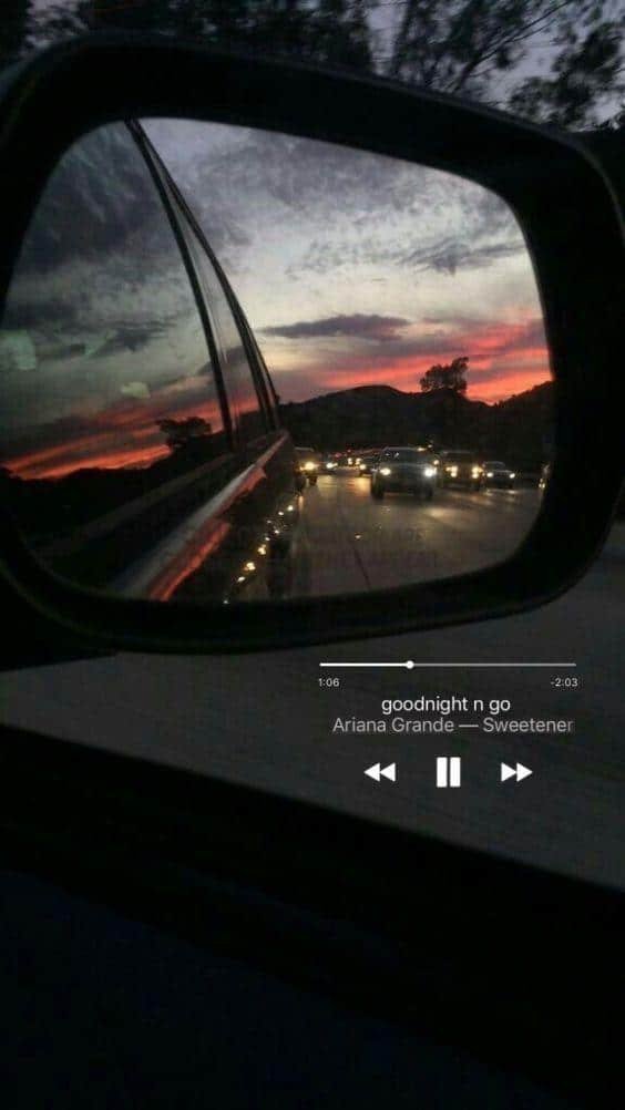 Atardecer en el retrovisor con el adhesivo de una canción