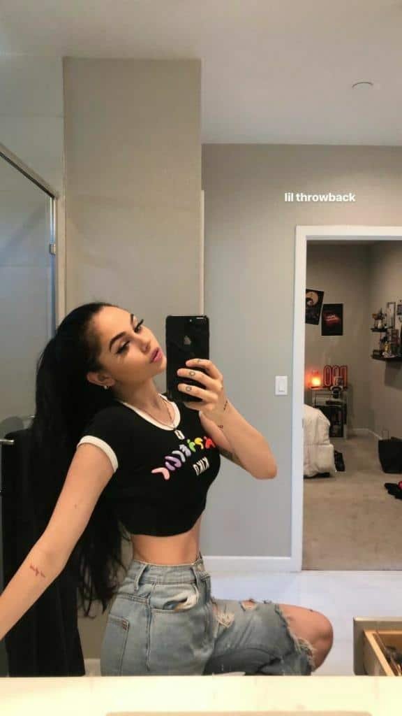 Cuerpo entero en el espejo con top negro y jeans rotos