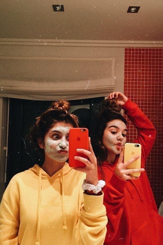 Dos amigas con mascarilla facial en el espejo del baño