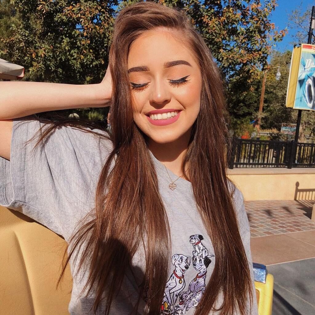 Chica sentada con la mano en el pelo y camiseta blanca