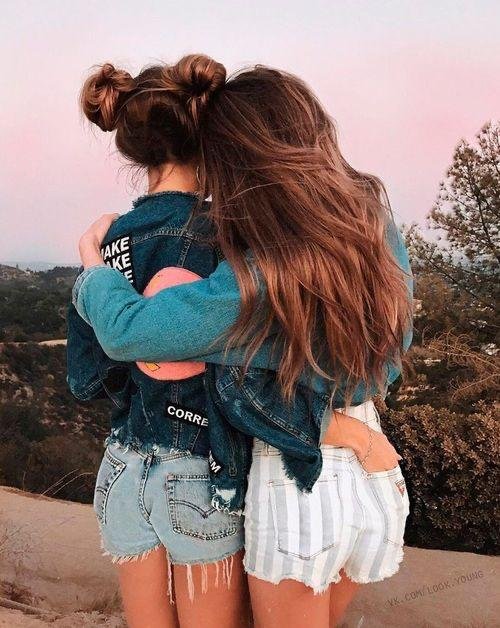 Dos amigas abrazadas de espaldas al atardecer