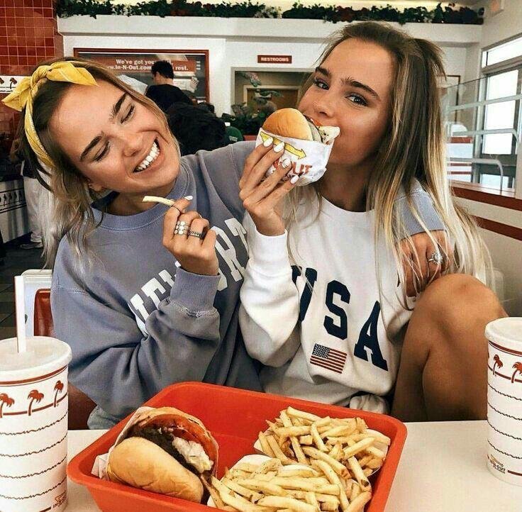 Dos amigas comiendo hamburguesas en un restaurante