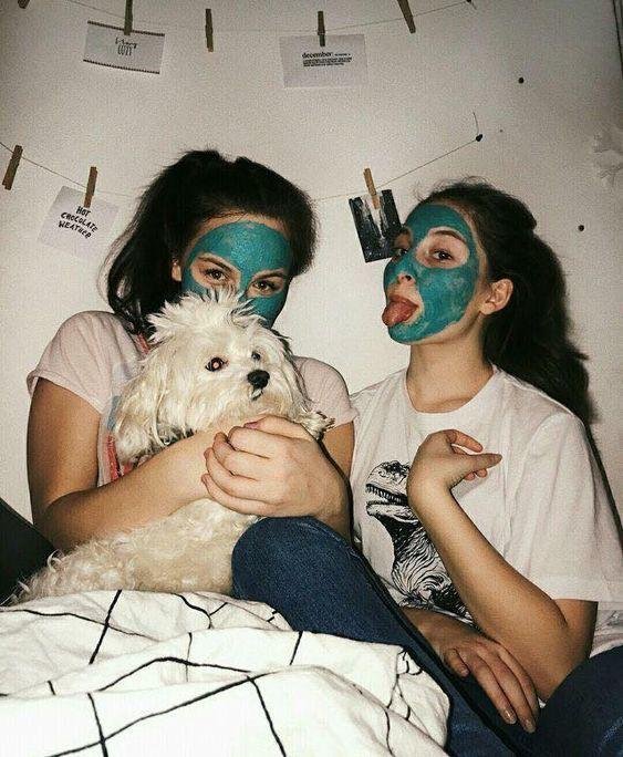 Dos amigas en la cama con mascarilla facial y un perro