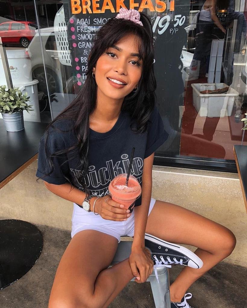 Chica sentada en la calle con camiseta negra y batido