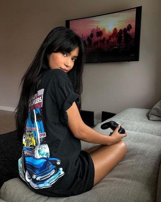 Chica sentada en la cama con camiseta larga estampada