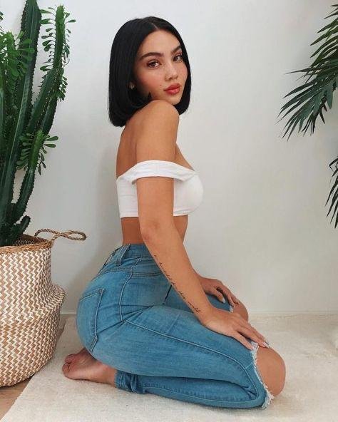 Chica de rodillas con top blanco y jeans