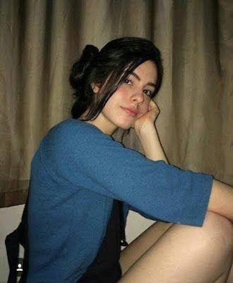 Chica sentada con jersey azul y la mano en la cara