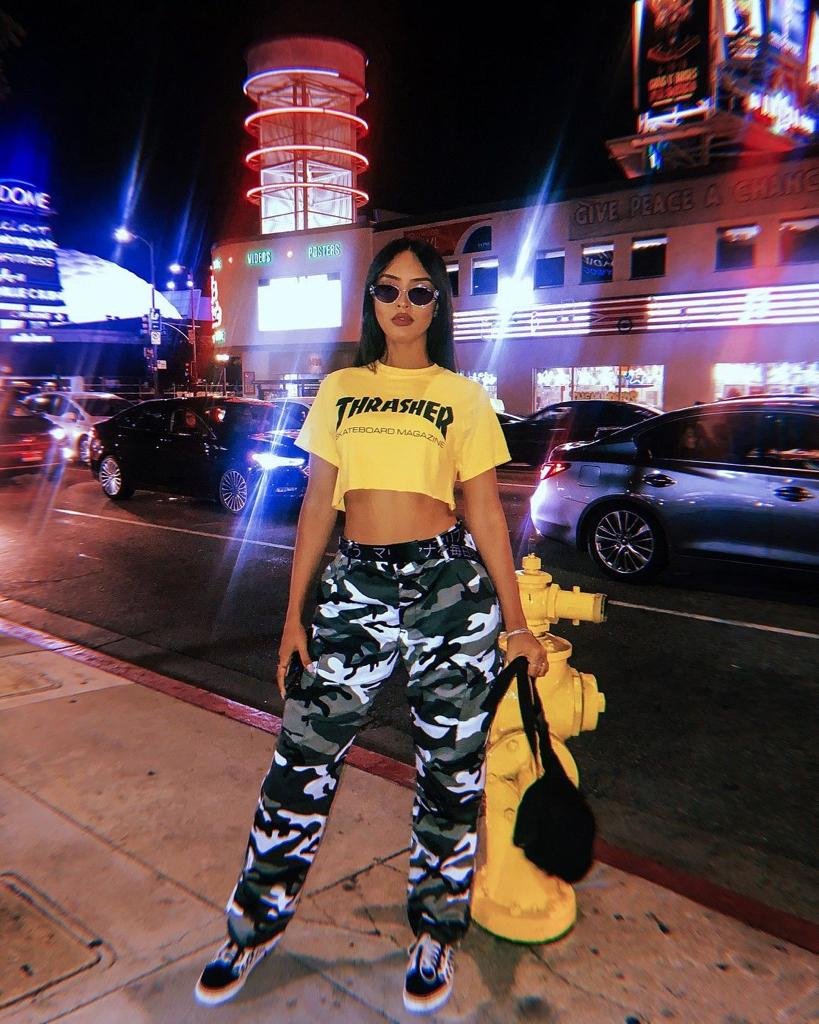 Chica con camiseta amarilla y pantalón militar de noche