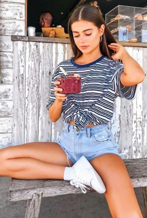 Chica sentada en un banco de madera con shorts vaqueros