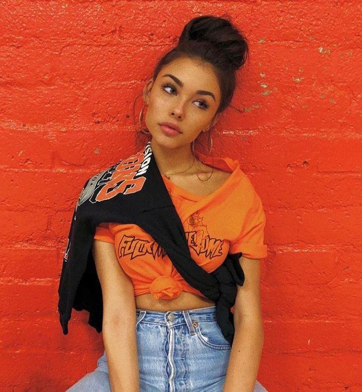 Chica con camiseta naranja contra una pared roja