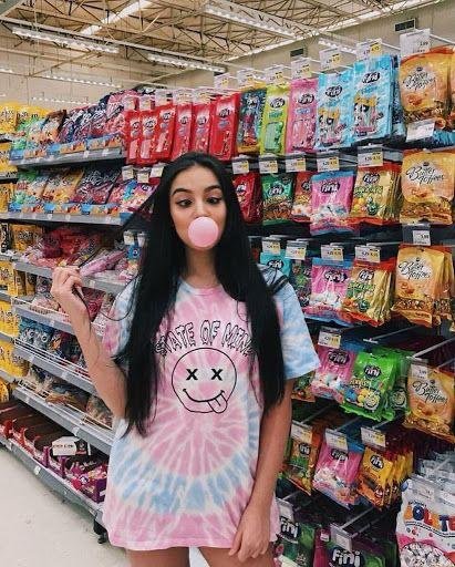Chica haciendo un globo de chicle en un supermercado