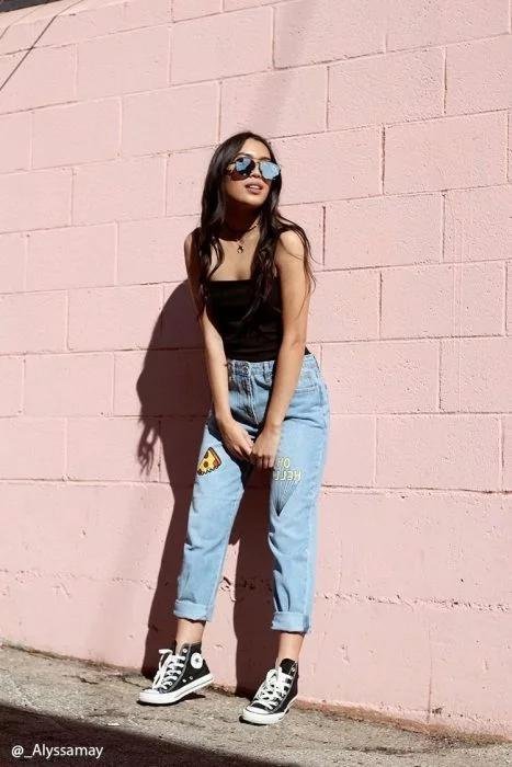 Chica de pie contra una pared rosa con gafas de sol
