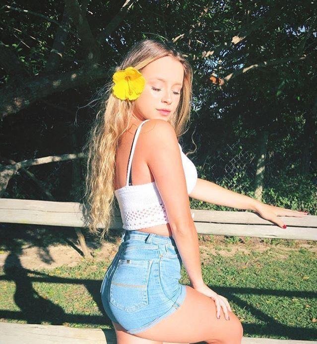 Chica apoyada en una valla de madera con una flor en el pelo