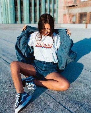 Chica sentada en la acera con chaqueta vaquera abierta