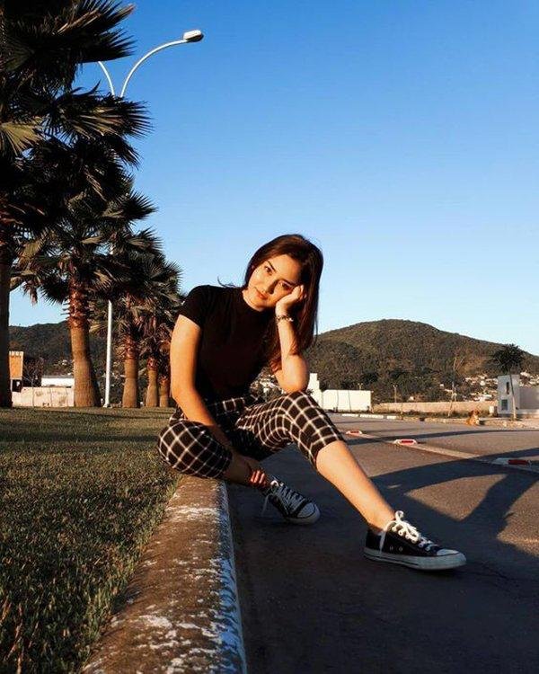 Chica sentada en un muro con palmeras de fondo