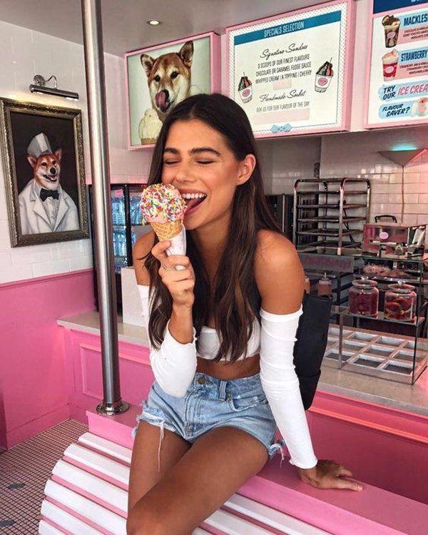 Chica sentada comiendo un helado en una heladería rosa